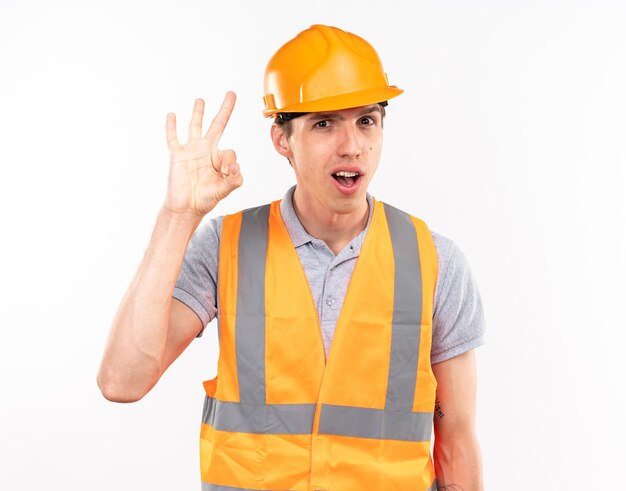 Souriant jeune homme constructeur en uniforme montrant trois