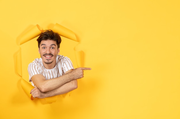 Photo gratuite souriant jeune homme sur la surface du papier jaune déchiré