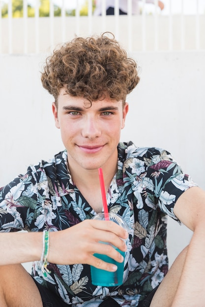 Souriant jeune homme avec un verre de jus