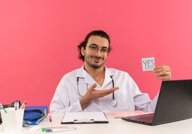 Souriant jeune médecin de sexe masculin avec des lunettes médicales portant une robe médicale avec stéthoscope