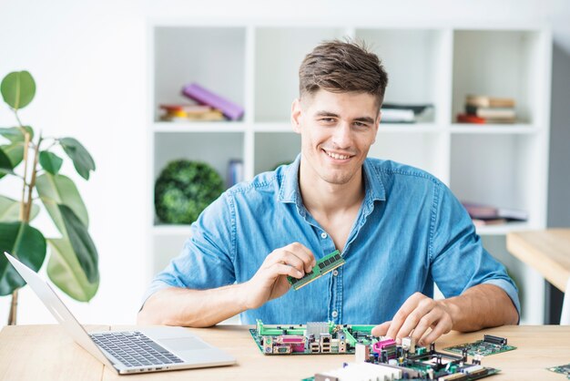 Souriant jeune technicien informatique mâle avec matériel informatique