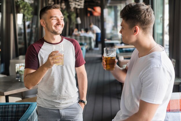 Souriant jeunes amis masculins tenant un verre d&#39;ours