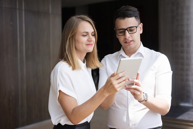 Souriant de jeunes collègues en réseau sur une tablette numérique.