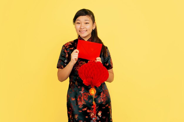 Souriant avec lanterne et enveloppe. Joyeux nouvel an chinois 2020. Portrait de jeune fille asiatique sur fond jaune. Modèle féminin en vêtements traditionnels a l'air heureux. Copyspace.