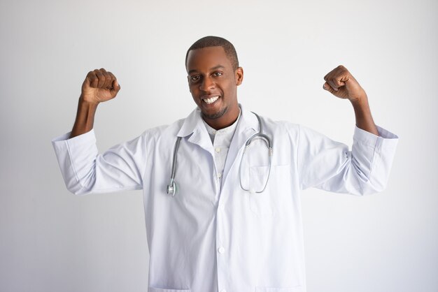 Souriant noir homme médecin pompant les poings et célébrant le succès.