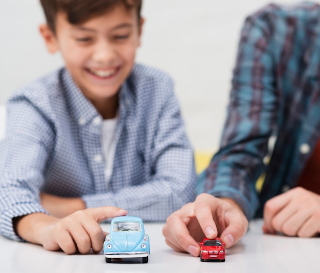 Photo gratuite souriant petit garçon jouant avec de petites voitures