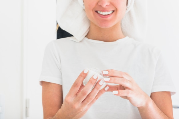 Souriant portrait de femme tenant une bouteille de crème hydratante dans les mains