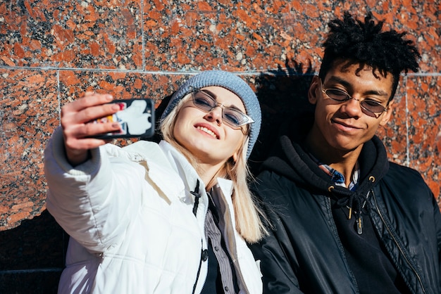 Photo gratuite souriant portrait d'un jeune couple prenant selfie sur téléphone mobile