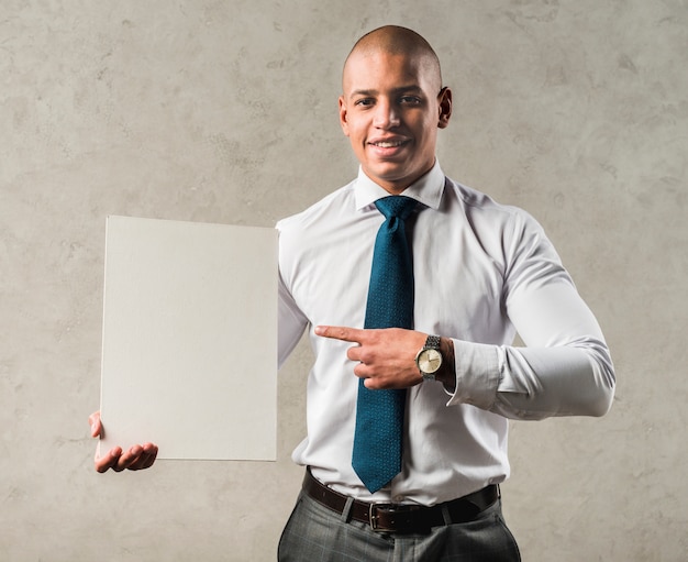 Souriant portrait d&#39;un jeune homme d&#39;affaires pointant son doigt vers une plaque vierge