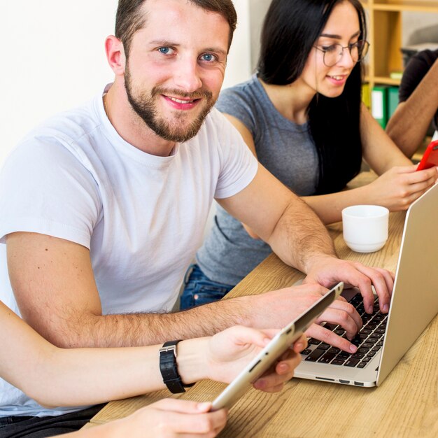 Souriant portrait d&#39;un jeune homme travaillant sur un ordinateur portable sur un bureau en bois