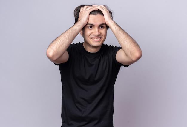 Souriant regardant le côté jeune beau mec portant un t-shirt noir attrapé la tête isolée sur un mur blanc