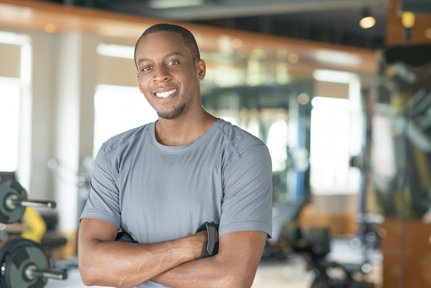 Souriant sportif homme noir debout avec les bras croisés