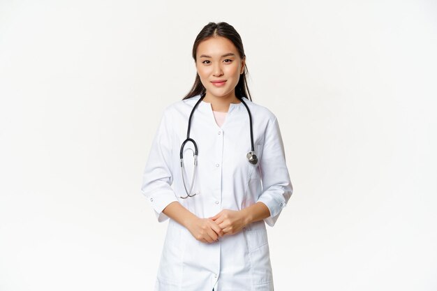 Souriant travailleur médical asiatique avec stéthoscope portant un uniforme de médecin à la recherche d'aide au patient stan ...