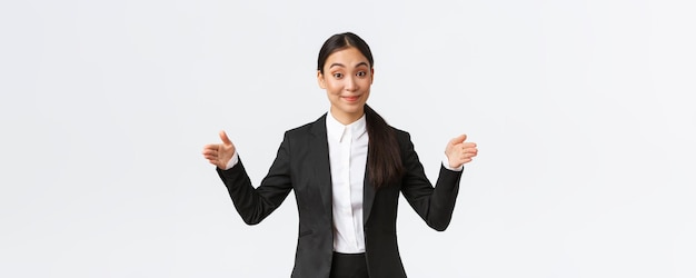 Souriante agréable femme d'affaires asiatique vendeuse en costume noir essayant de vendre quelque chose façonnant un gros objet présenter le produit au client ayant une présentation commerciale du projet fond blanc