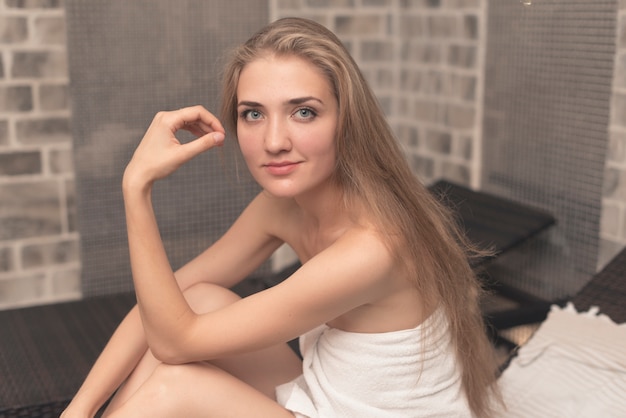 Photo gratuite souriante belle jeune femme assise sur une chaise longue dans le spa