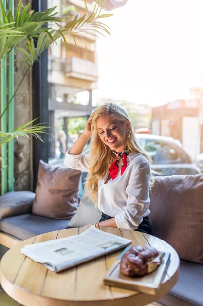 Souriante belle jeune femme assise dans le restaurant avec du pain cuit au four sur table