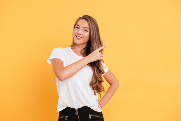 Souriante belle jeune femme pointant vers le fond.