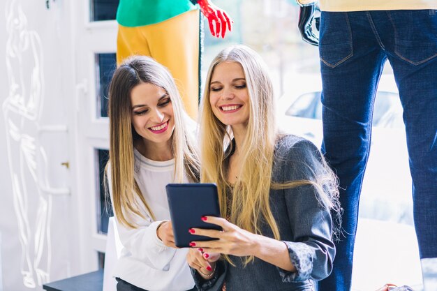 Souriante blonde jeune femme regardant une tablette numérique dans la boutique