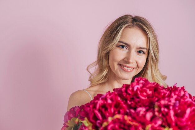 Souriante blonde jeune femme tenant un bouquet de fleurs