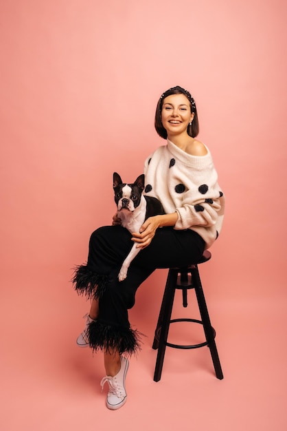 Souriante caucasienne jeune fille brune se présentant à la caméra avec des bouledogues français sur fond rose Bonne relation entre les animaux et les gens concept