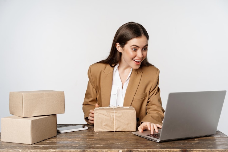 Photo gratuit souriante femme d'affaires heureuse travaillant dans son bureau avec des commandes de processus de livraison de colis sur son ordinateur portable...