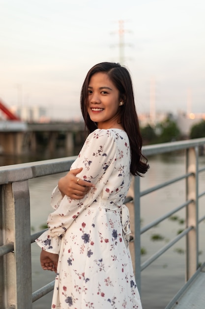 Souriante fille vietnamienne aux cheveux noirs debout sur un pont