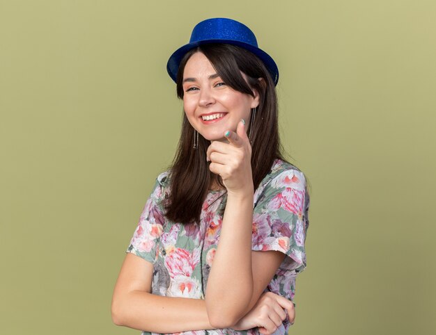 Souriante jeune belle fille portant un chapeau de fête vous montrant le geste