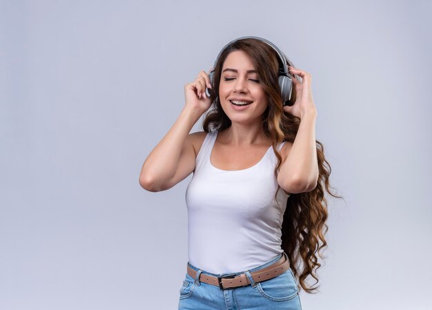 Souriante jeune belle fille portant des écouteurs, écouter de la musique avec les yeux fermés avec copie espace