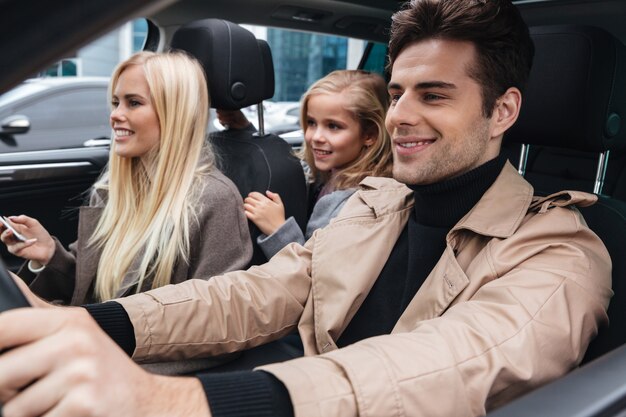 Souriante jeune famille assise dans la voiture