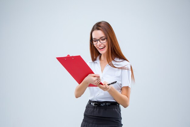 Souriante jeune femme d'affaires dans des verres avec un stylo et une tablette pour des notes sur un fond gris