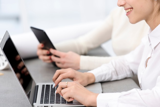 Photo gratuite souriante jeune femme d'affaires tapant sur un ordinateur portable sur le bureau