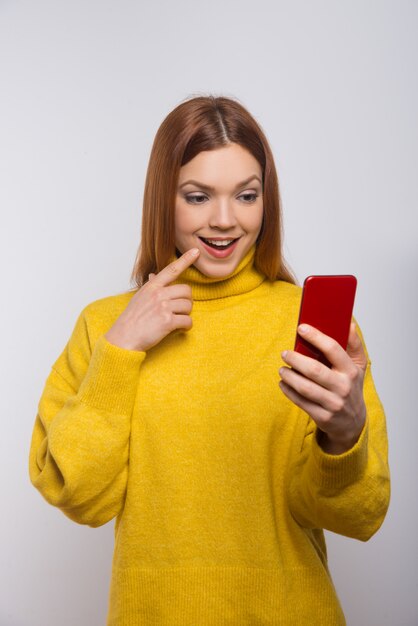 Souriante jeune femme à l'aide de smartphone