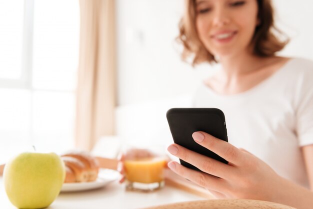 Souriante jeune femme assise à l'intérieur discutant par téléphone.