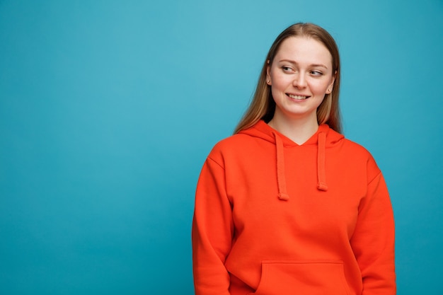 Souriante jeune femme blonde regardant le côté