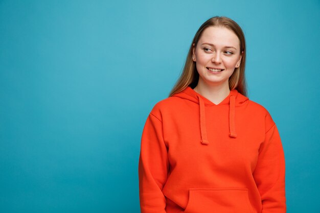 Souriante jeune femme blonde regardant le côté