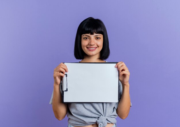 Souriante jeune femme caucasienne brune détient le presse-papiers