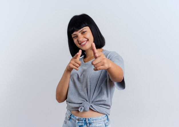 Souriante jeune femme caucasienne brune regarde à deux mains