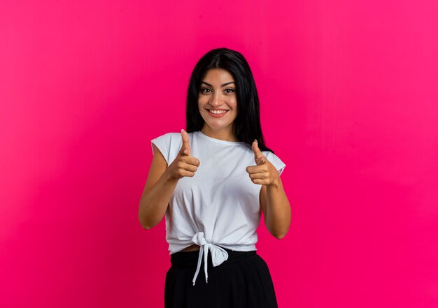 Souriante jeune femme caucasienne pointe la caméra à deux mains