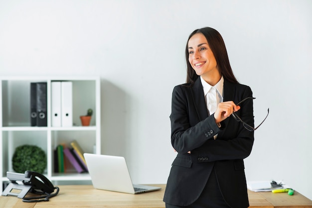 Souriante jeune femme debout devant le bureau