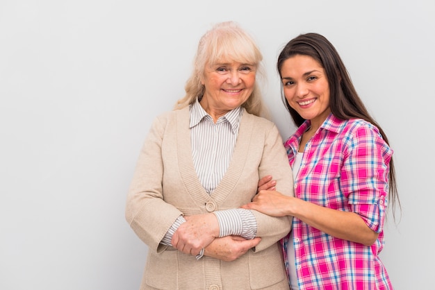 Souriante jeune femme debout avec sa mère sur fond blanc