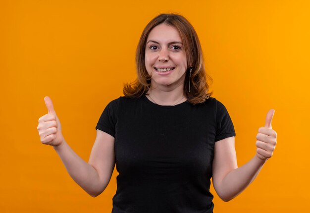 Souriante jeune femme décontractée montrant les pouces vers le haut sur l'espace orange isolé