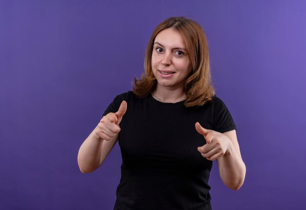 Souriante jeune femme décontractée pointant sur l'espace violet isolé avec espace copie