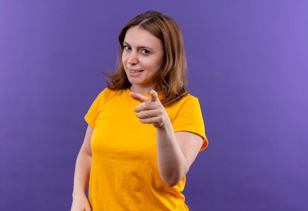 Souriante jeune femme décontractée pointant sur l'espace violet isolé avec espace copie