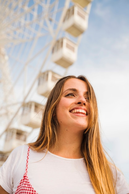 Photo gratuite souriante jeune femme devant la grande roue