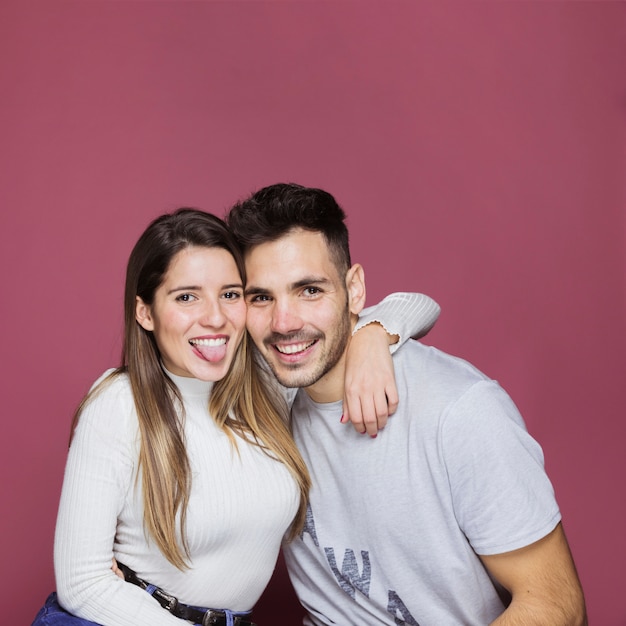 Souriante jeune femme étreignant l&#39;homme et montrant la langue