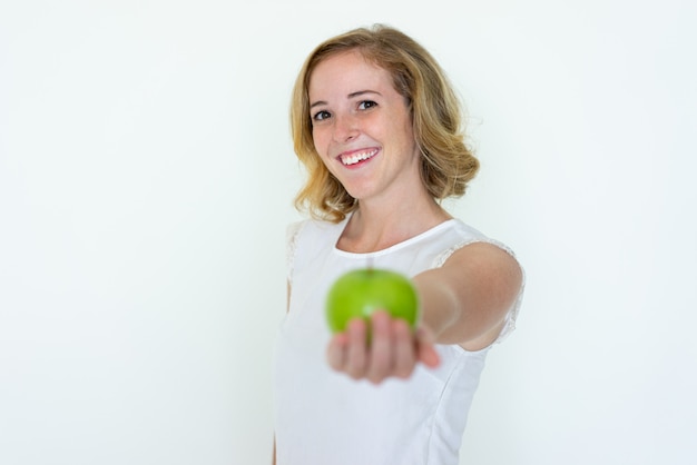 Souriante jeune femme jolie offrant une pomme verte floue