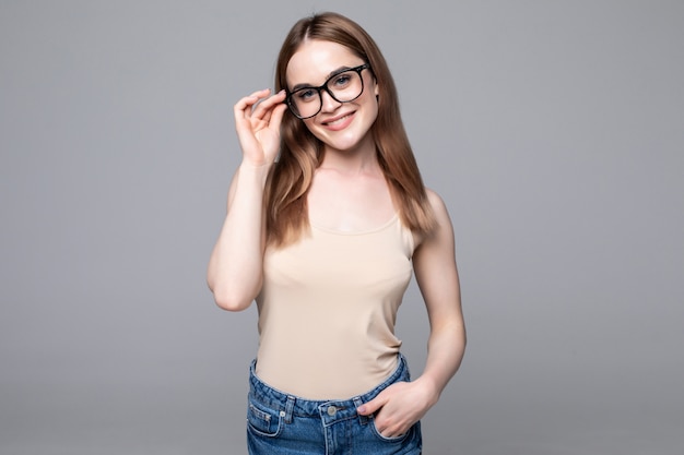 Souriante jeune femme avec des lunettes sur mur gris