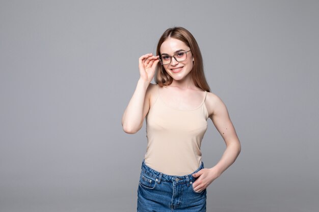 Souriante jeune femme avec des lunettes sur mur gris