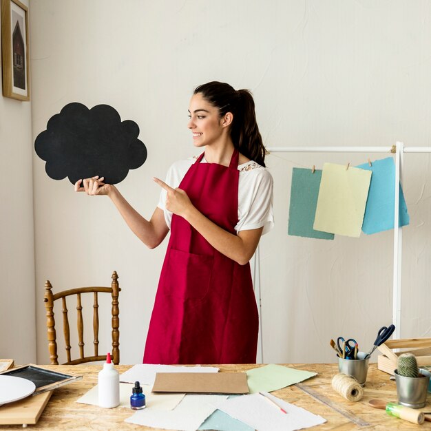 Souriante jeune femme montrant une bulle de dialogue noir en papier