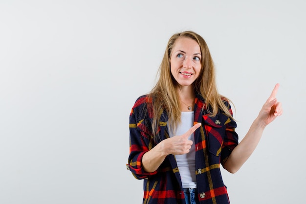 Souriante jeune femme montrant la droite avec ses doigts sur fond blanc